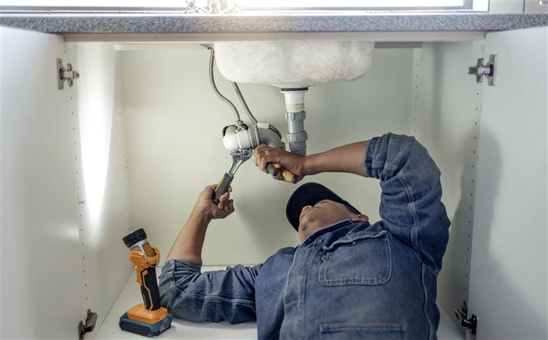 Plumber repairing pipes beneath a bathroom sink in Lutz