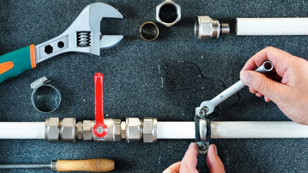 Plumber repairing a pipe valve with an adjustable wrench in Lutz