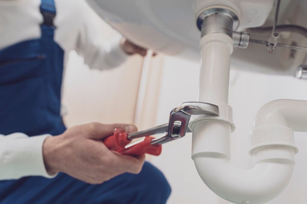 Plumber repairing a white drain pipe beneath a sink in Lutz