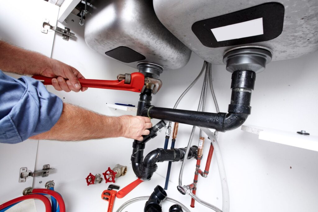 Plumber repairing drain pipes beneath a kitchen sink in Lutz